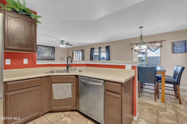 kitchen featuring sink, ceiling fan with notable chandelier, decorative light fixtures, stainless steel dishwasher, and kitchen peninsula