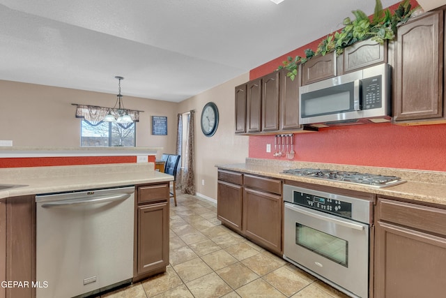 kitchen with pendant lighting, appliances with stainless steel finishes, light tile patterned flooring, and a notable chandelier