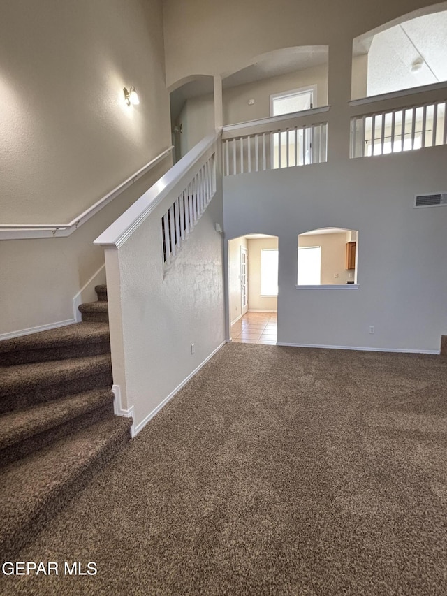 unfurnished living room featuring carpet flooring and a high ceiling