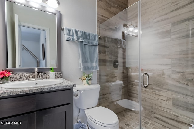 bathroom featuring vanity, toilet, and a shower with shower door