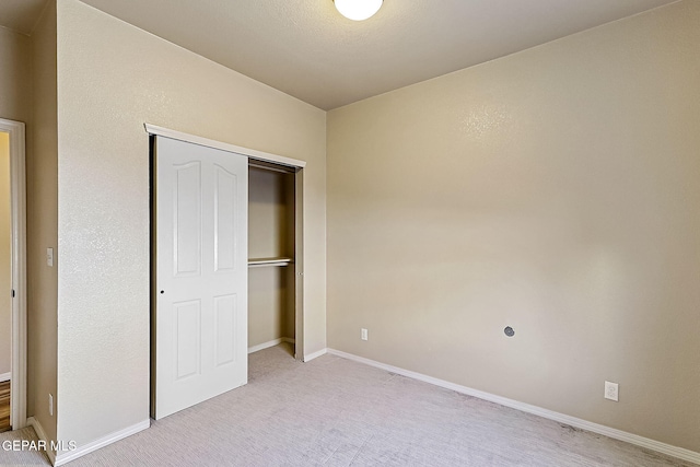 unfurnished bedroom with light carpet and a closet