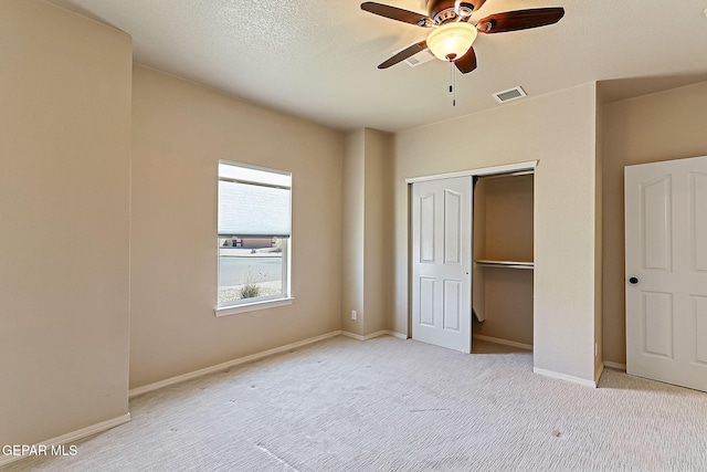 unfurnished bedroom with ceiling fan, light carpet, a textured ceiling, and a closet