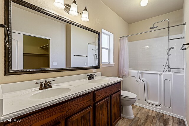 full bathroom featuring hardwood / wood-style flooring, vanity, toilet, and shower / tub combo