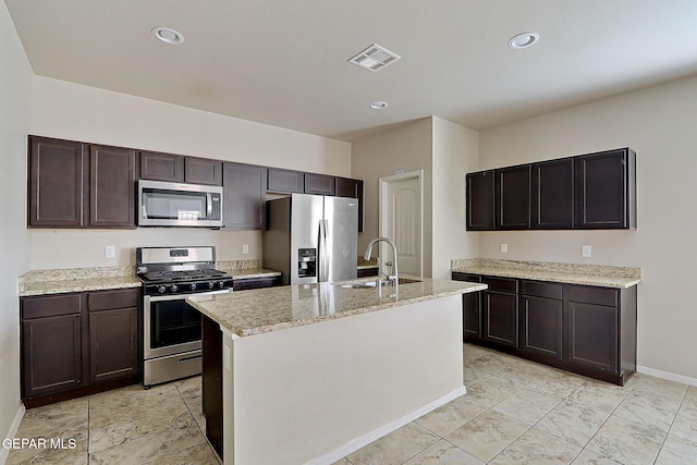 kitchen featuring dark brown cabinetry, sink, an island with sink, and appliances with stainless steel finishes