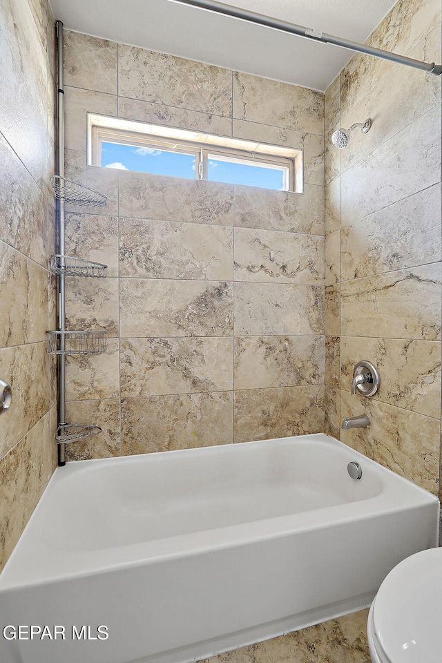 bathroom with tiled shower / bath combo and toilet