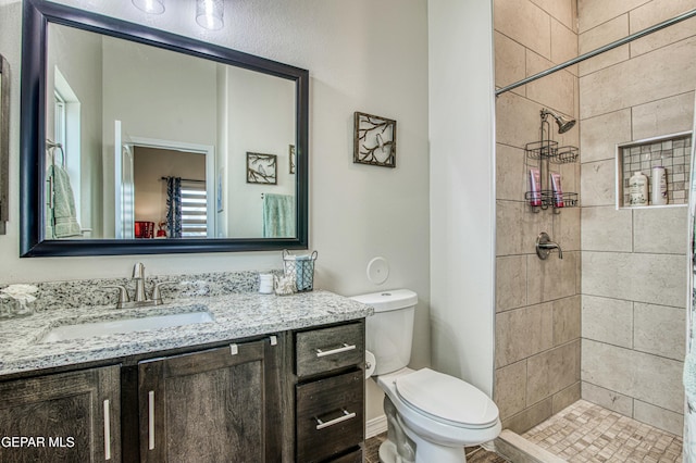 bathroom with vanity, toilet, and tiled shower