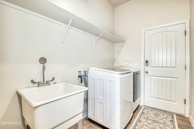 clothes washing area with separate washer and dryer, sink, and hardwood / wood-style floors