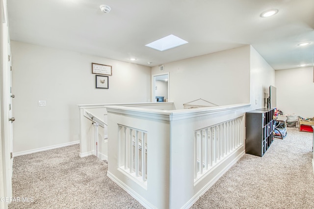 hallway featuring a skylight and light carpet