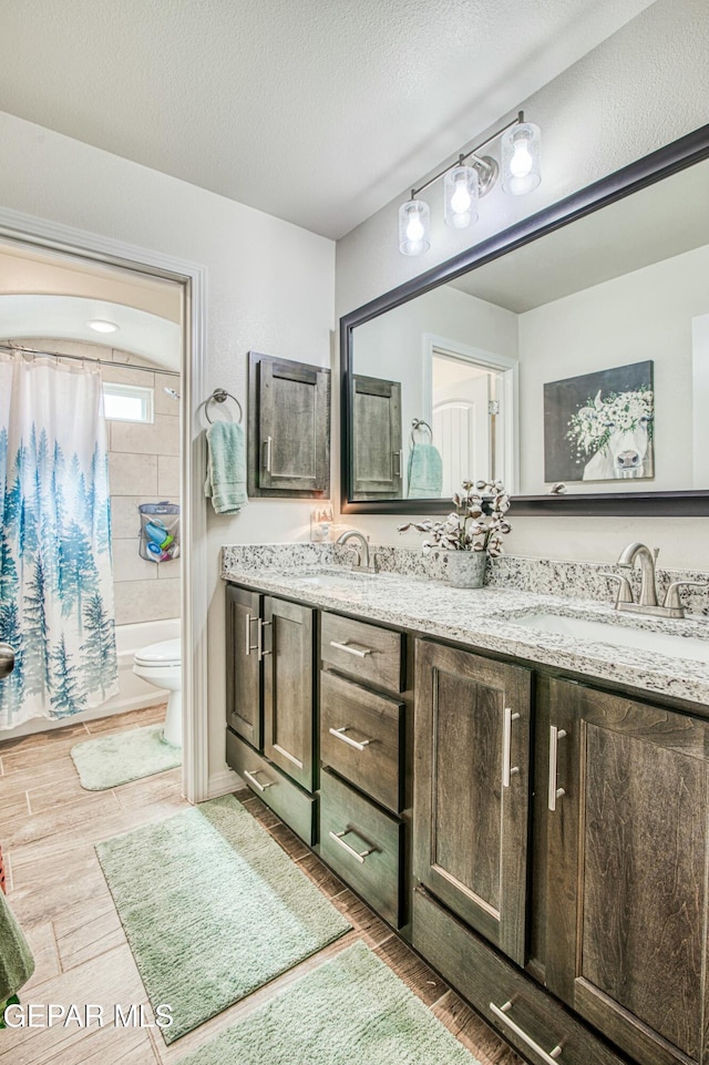 full bathroom featuring toilet, wood-type flooring, a textured ceiling, vanity, and shower / bath combo