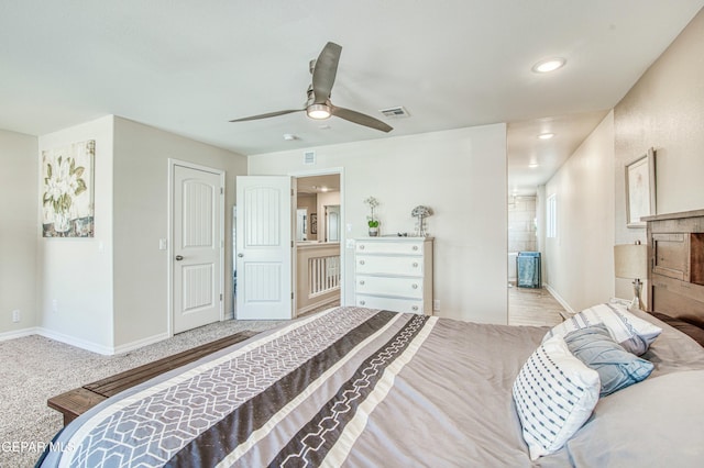 bedroom with ensuite bathroom, light colored carpet, and ceiling fan