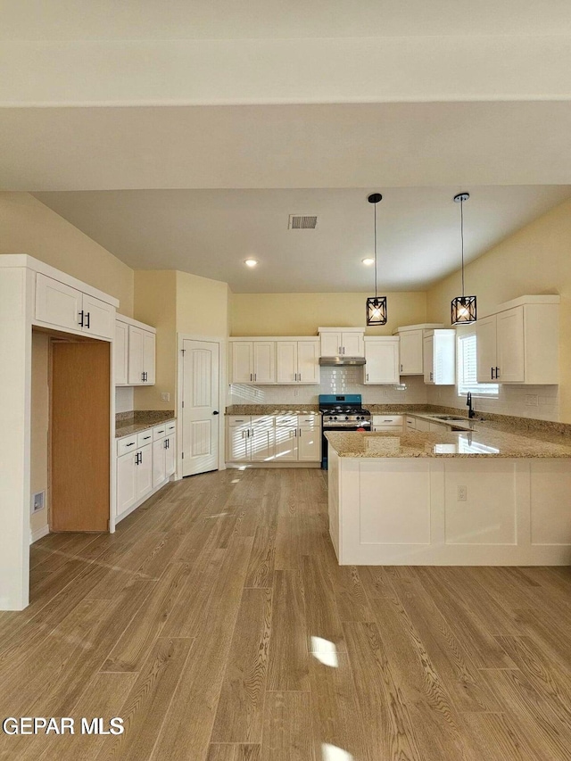 kitchen featuring decorative light fixtures, sink, white cabinets, light hardwood / wood-style floors, and stainless steel gas range