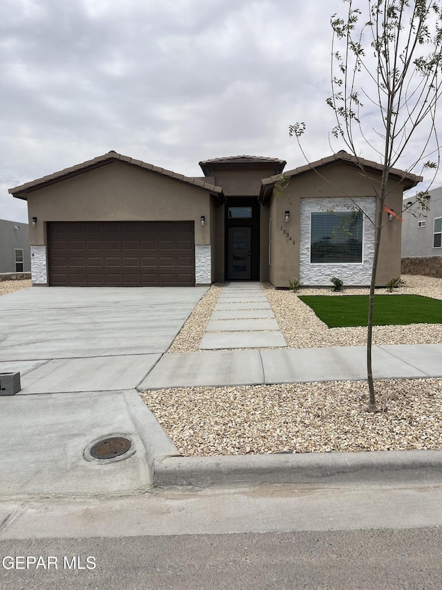216 Emerald Brass, Horizon City, TX 79928 - view of front facade featuring stucco siding, an attached garage, concrete driveway, and stone siding
