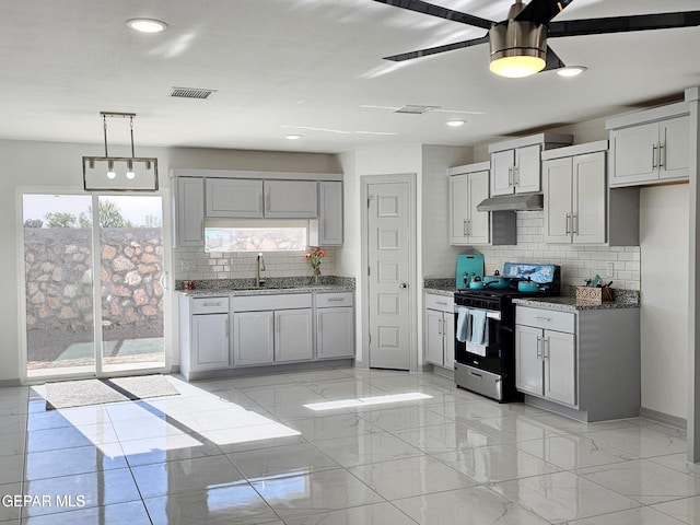 kitchen with stone countertops, sink, backsplash, hanging light fixtures, and stove