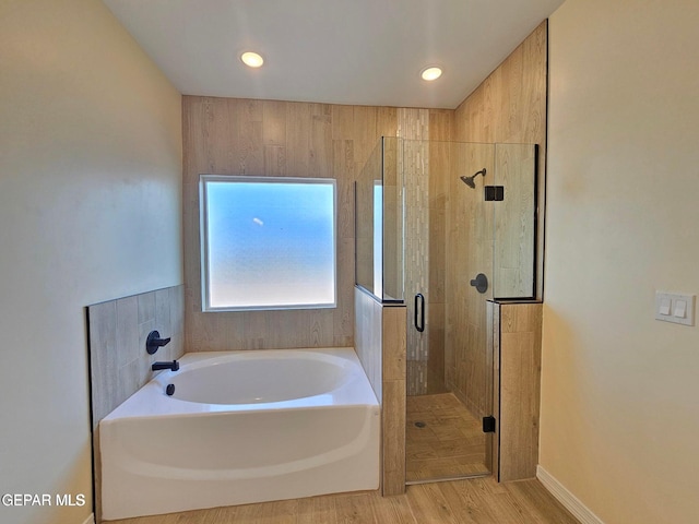 bathroom featuring wood-type flooring and shower with separate bathtub