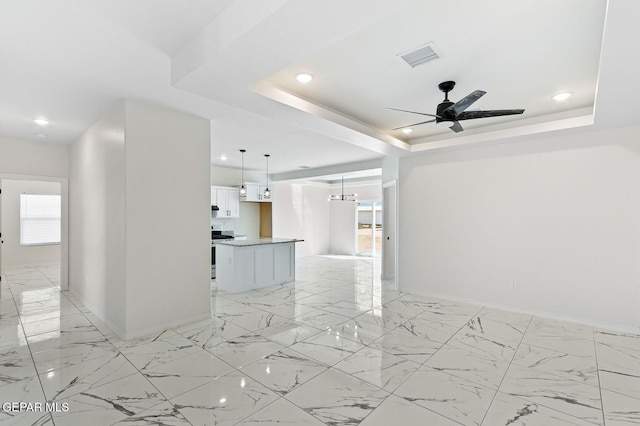 empty room featuring marble finish floor, a tray ceiling, recessed lighting, and baseboards