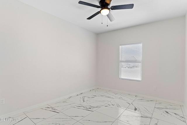 empty room featuring ceiling fan, marble finish floor, and baseboards