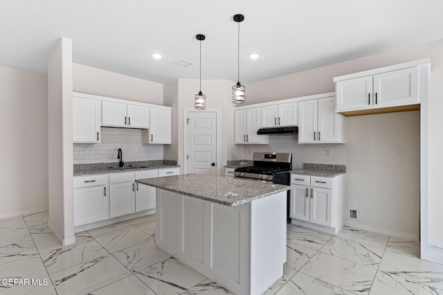 kitchen featuring under cabinet range hood, a sink, white cabinetry, marble finish floor, and stainless steel range with gas cooktop