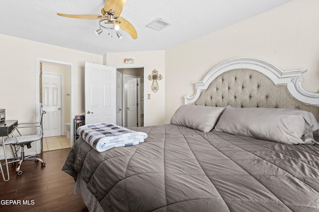 bedroom featuring dark hardwood / wood-style flooring, ceiling fan, and a textured ceiling