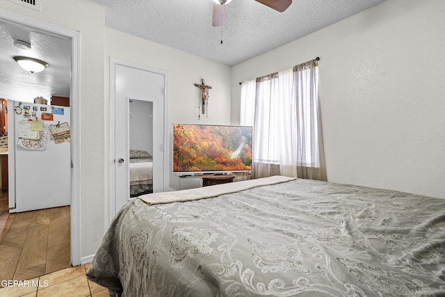 tiled bedroom with white refrigerator, ceiling fan, and a textured ceiling