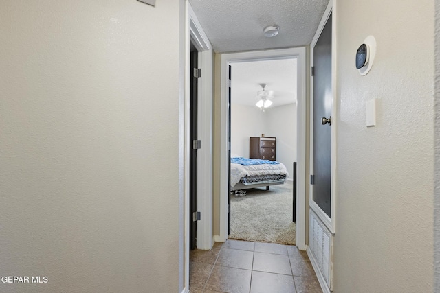 hall featuring a textured ceiling and light tile patterned flooring