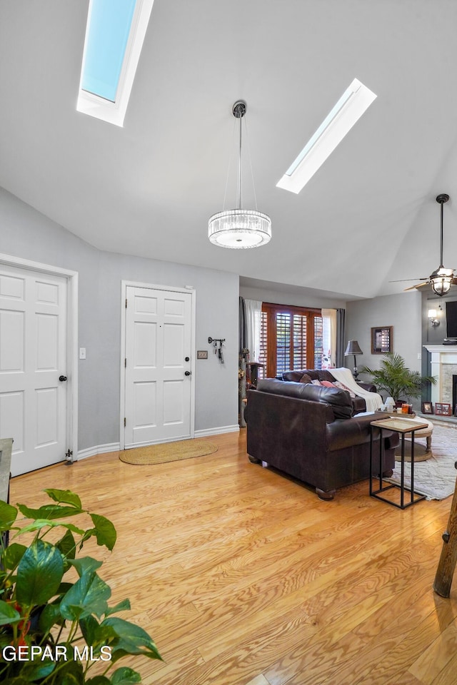 living room with ceiling fan, light hardwood / wood-style floors, and vaulted ceiling