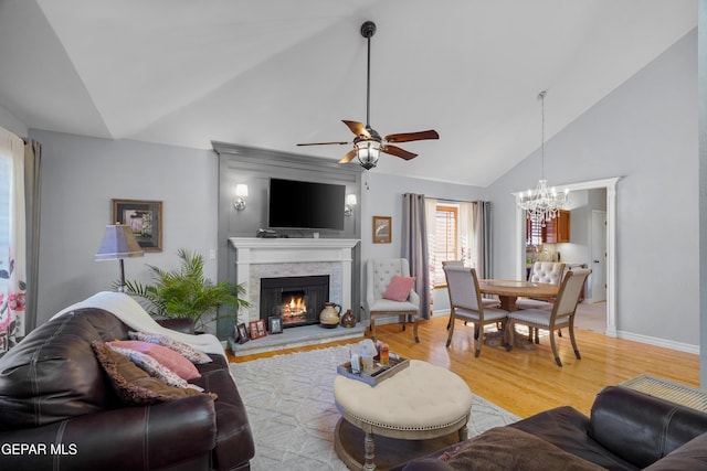 living room with ceiling fan with notable chandelier, wood-type flooring, and high vaulted ceiling