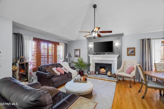 living room with ceiling fan, wood-type flooring, a fireplace, and vaulted ceiling