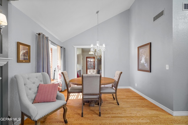 dining space featuring an inviting chandelier, high vaulted ceiling, and light hardwood / wood-style floors