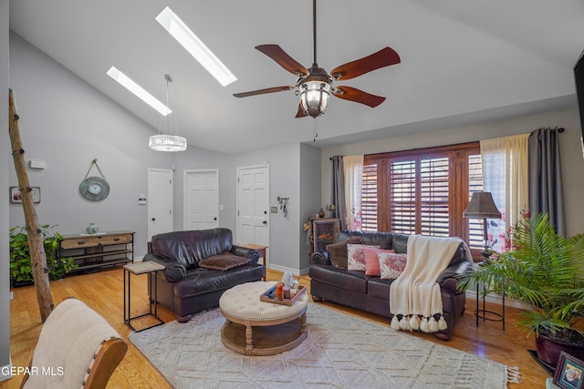 living room with ceiling fan, high vaulted ceiling, light hardwood / wood-style floors, and a skylight