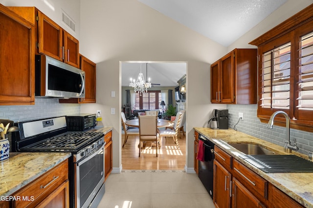 kitchen featuring light stone counters, lofted ceiling, appliances with stainless steel finishes, and sink