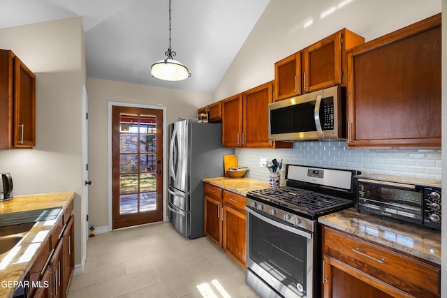 kitchen featuring pendant lighting, lofted ceiling, appliances with stainless steel finishes, tasteful backsplash, and light stone countertops