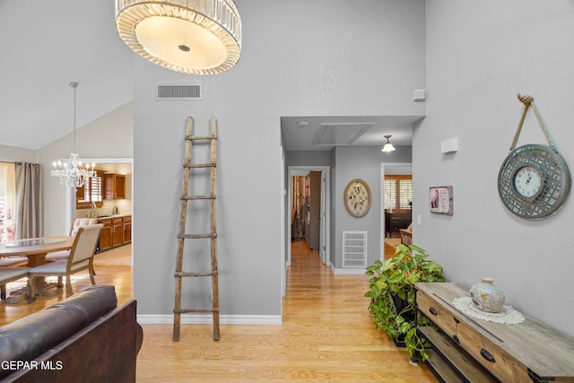 foyer entrance with a notable chandelier, light hardwood / wood-style flooring, and high vaulted ceiling