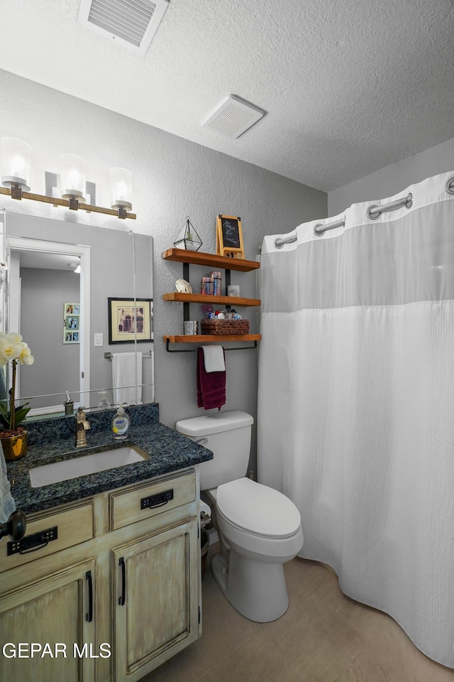 bathroom featuring vanity, toilet, and a textured ceiling