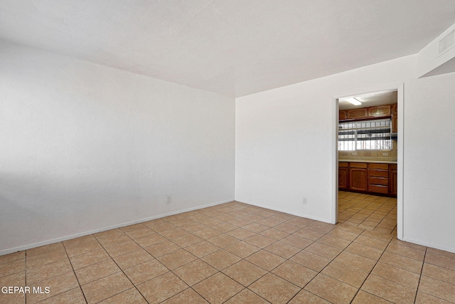 unfurnished room featuring light tile patterned floors and baseboards