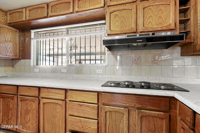 kitchen with brown cabinets, light countertops, under cabinet range hood, and black electric cooktop