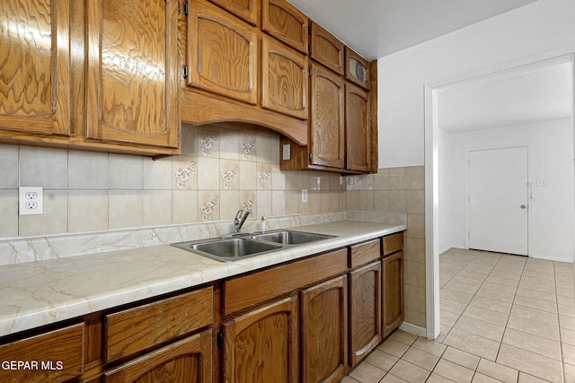 kitchen featuring brown cabinets, light countertops, a sink, and light tile patterned flooring