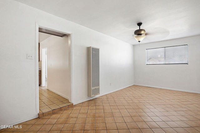 spare room featuring light tile patterned floors, baseboards, a heating unit, and a ceiling fan