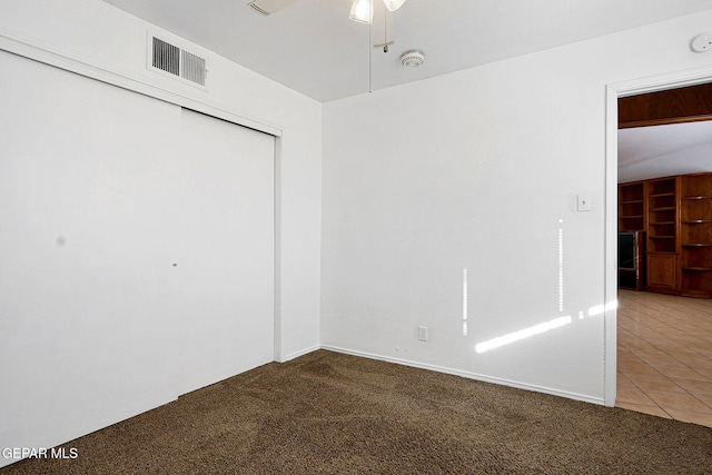 unfurnished bedroom with visible vents, ceiling fan, tile patterned floors, carpet floors, and a closet