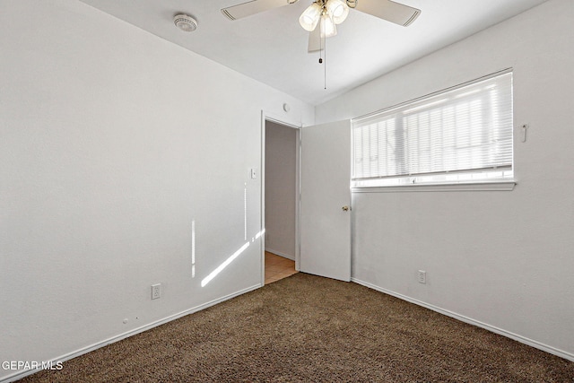 carpeted spare room with a ceiling fan and baseboards