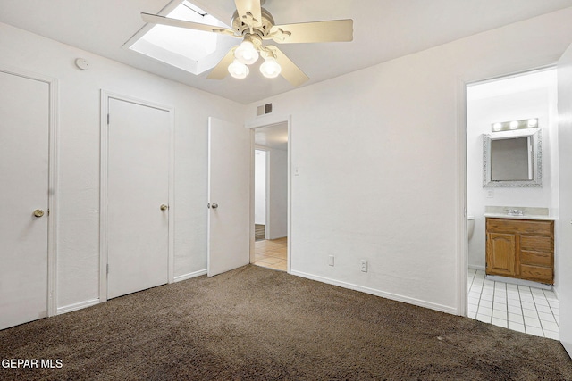 unfurnished bedroom featuring light tile patterned flooring, connected bathroom, visible vents, and light colored carpet