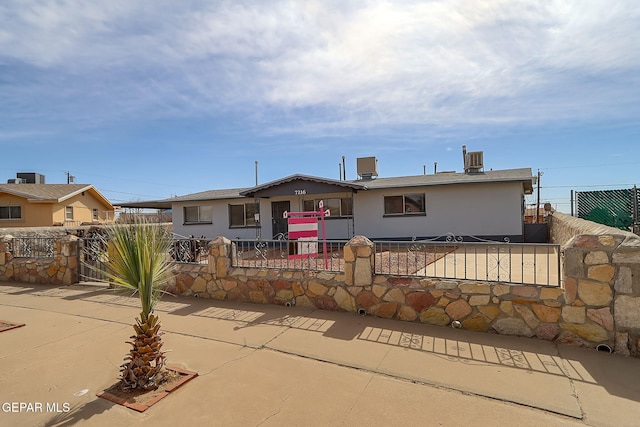 ranch-style house with central AC unit and a fenced front yard