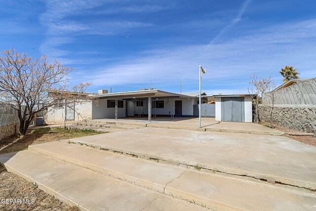 back of property with an outbuilding, fence, a storage shed, and a patio