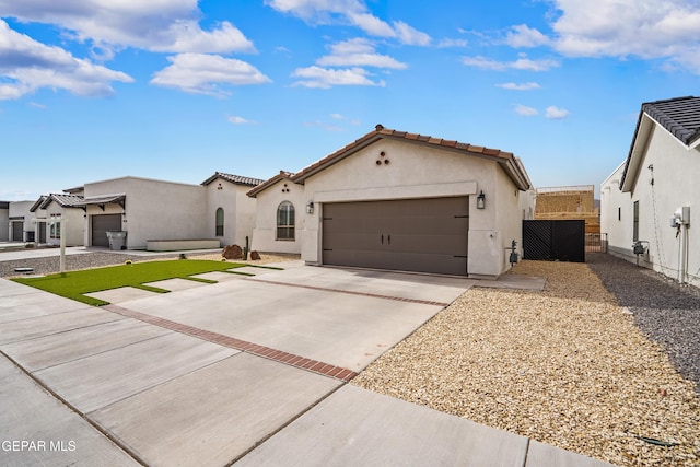 mediterranean / spanish-style home with stucco siding, an attached garage, fence, driveway, and a tiled roof