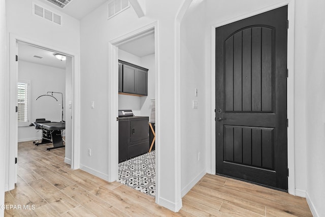 foyer with baseboards, washing machine and dryer, visible vents, and light wood-style floors