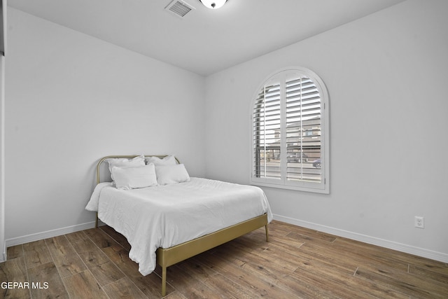 bedroom featuring baseboards, visible vents, and wood finished floors