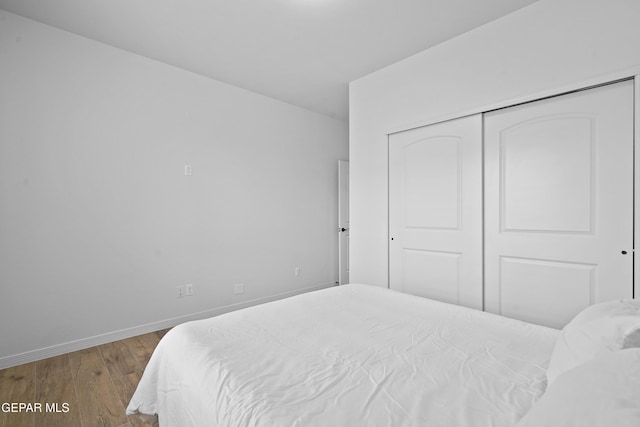 bedroom with a closet, baseboards, and wood finished floors