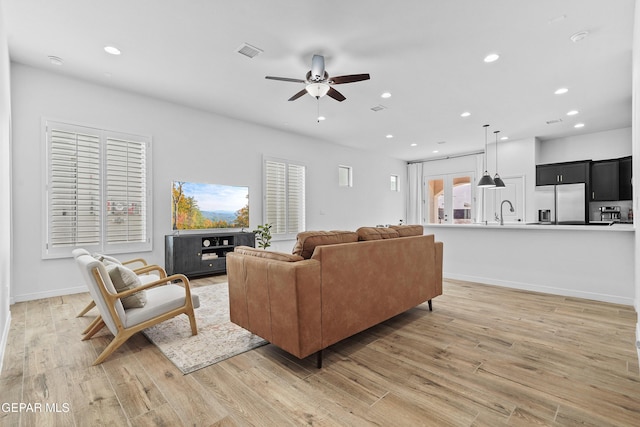 living area featuring recessed lighting, a ceiling fan, baseboards, visible vents, and light wood-type flooring