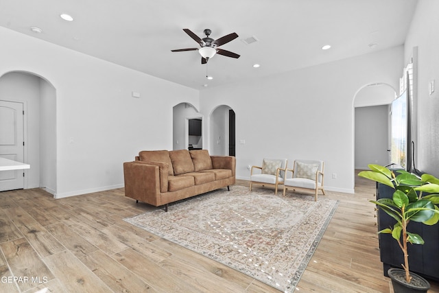 living area with arched walkways, visible vents, light wood-style flooring, and recessed lighting