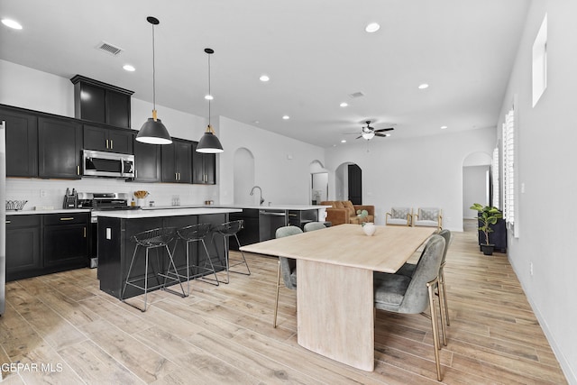 kitchen with appliances with stainless steel finishes, light countertops, a center island with sink, and a kitchen breakfast bar