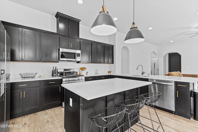 kitchen featuring a sink, stainless steel appliances, light countertops, and pendant lighting